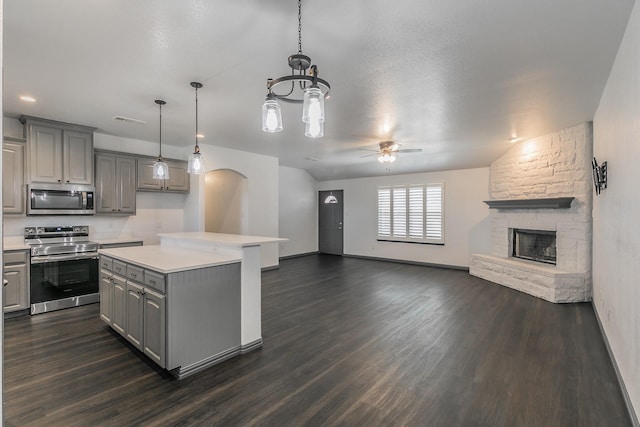 kitchen featuring open floor plan, a center island, gray cabinets, stainless steel appliances, and light countertops