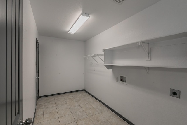 laundry room with laundry area, baseboards, hookup for a washing machine, hookup for an electric dryer, and light tile patterned flooring