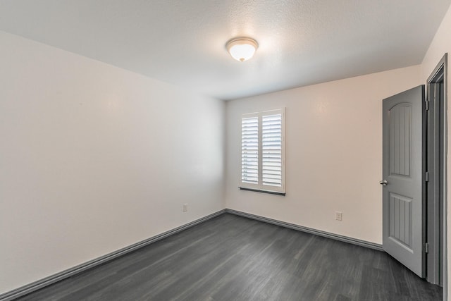 spare room featuring a textured ceiling, baseboards, and dark wood-style flooring