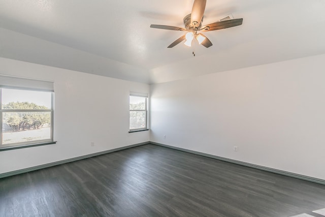 empty room featuring a ceiling fan, vaulted ceiling, dark wood finished floors, and baseboards