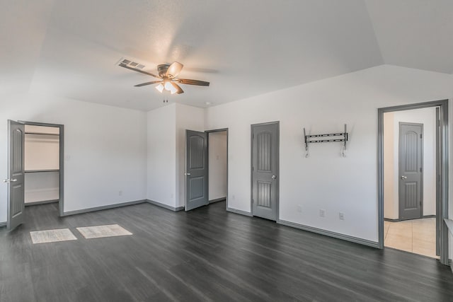 unfurnished bedroom featuring lofted ceiling, ceiling fan, baseboards, and dark wood-type flooring