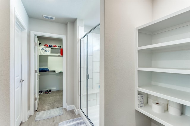 bathroom with hardwood / wood-style flooring and walk in shower