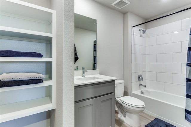 full bathroom featuring hardwood / wood-style flooring, vanity, tiled shower / bath combo, and toilet