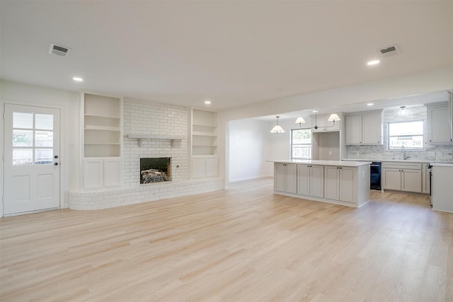 unfurnished living room with plenty of natural light, sink, a fireplace, and light hardwood / wood-style floors