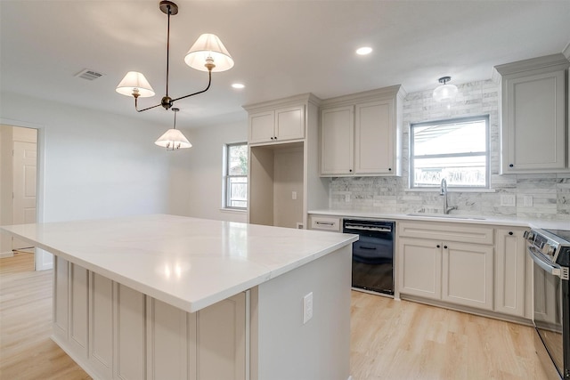 kitchen featuring a kitchen island, dishwasher, sink, hanging light fixtures, and electric range