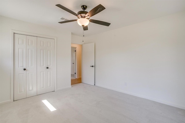 unfurnished bedroom with ceiling fan, light carpet, and a closet