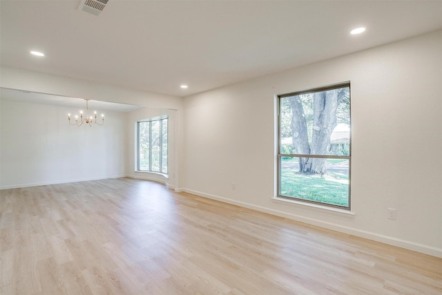 unfurnished room featuring plenty of natural light, light hardwood / wood-style flooring, and a notable chandelier