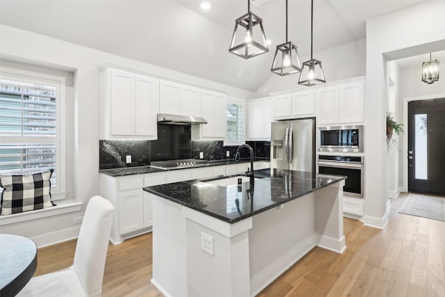 kitchen featuring stainless steel appliances, white cabinetry, pendant lighting, and a center island with sink