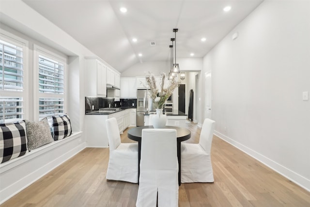 dining area with vaulted ceiling and light hardwood / wood-style floors