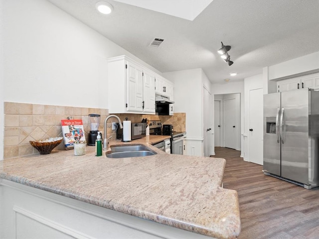 kitchen featuring sink, appliances with stainless steel finishes, white cabinetry, decorative backsplash, and kitchen peninsula