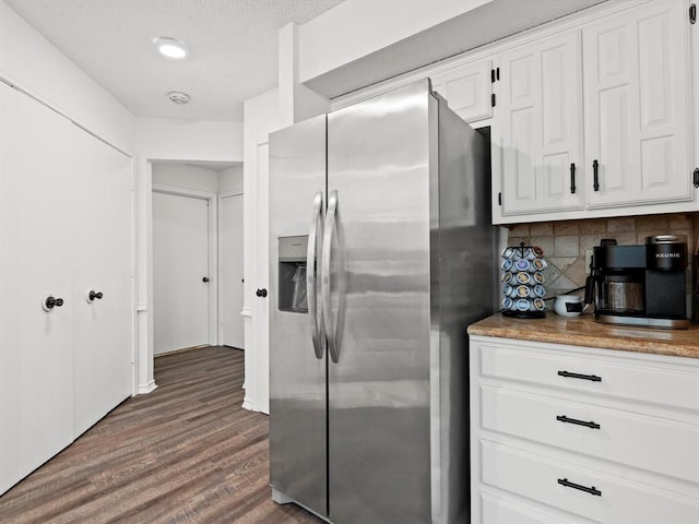 kitchen with white cabinetry, a textured ceiling, dark hardwood / wood-style flooring, stainless steel fridge with ice dispenser, and decorative backsplash