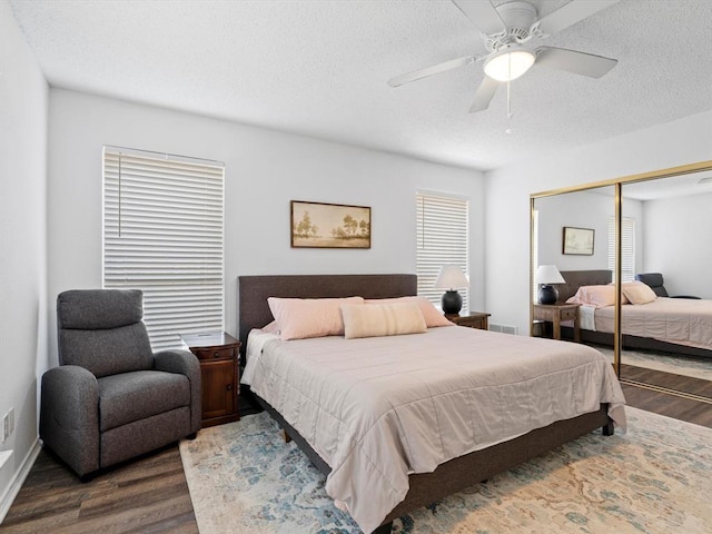 bedroom with dark wood-type flooring, ceiling fan, multiple windows, and a closet