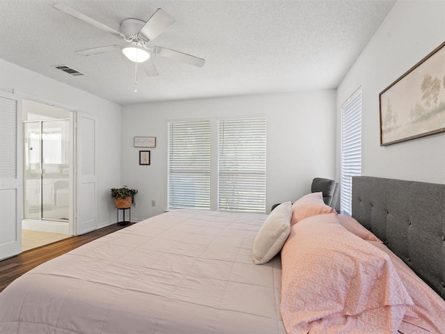 bedroom featuring ceiling fan, ensuite bathroom, multiple windows, and a textured ceiling