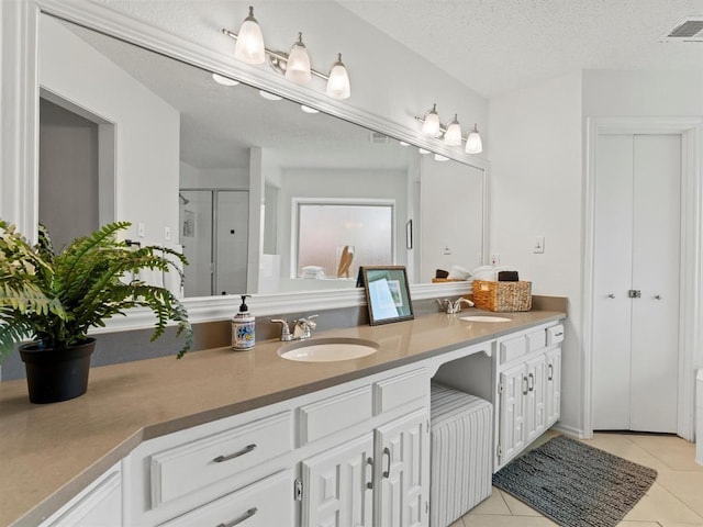 bathroom with tile patterned floors, an enclosed shower, vanity, and a textured ceiling