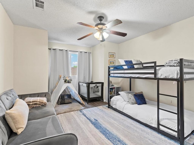 bedroom with a textured ceiling, wood-type flooring, and ceiling fan