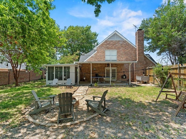 rear view of house with a lawn, a sunroom, and a patio area