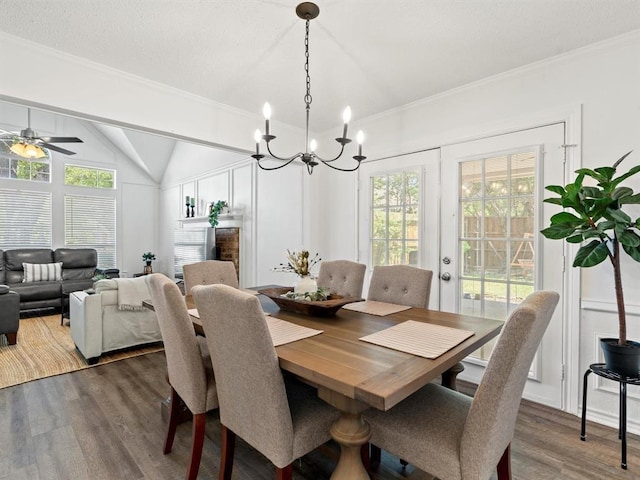 dining space featuring lofted ceiling, ornamental molding, dark hardwood / wood-style flooring, and ceiling fan with notable chandelier