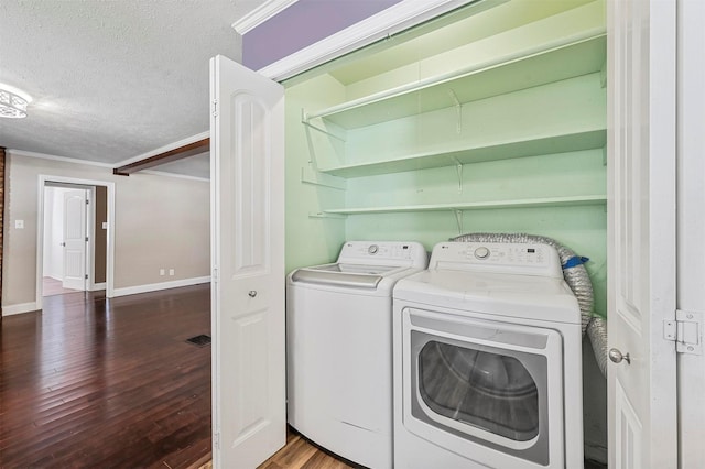 clothes washing area with crown molding, dark hardwood / wood-style floors, washing machine and clothes dryer, and a textured ceiling