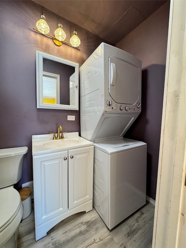 washroom featuring stacked washer / drying machine, light hardwood / wood-style floors, and sink