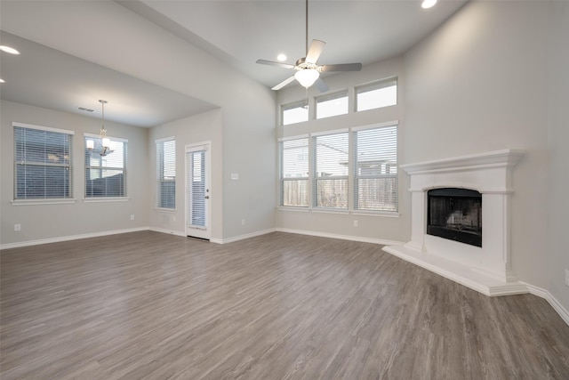 unfurnished living room featuring dark hardwood / wood-style flooring and ceiling fan with notable chandelier