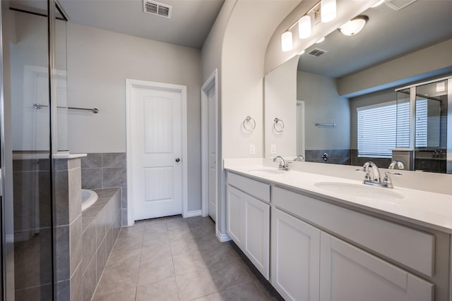 bathroom featuring tile patterned flooring, vanity, and a relaxing tiled tub