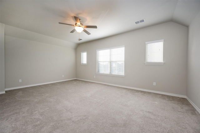 empty room featuring vaulted ceiling, carpet flooring, and a wealth of natural light