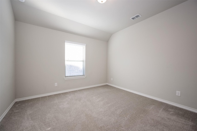 carpeted empty room with lofted ceiling