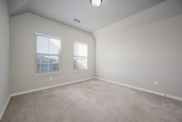 carpeted empty room with vaulted ceiling