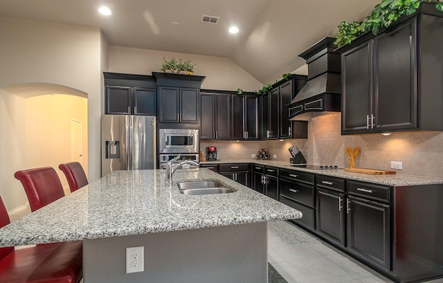 kitchen with backsplash, arched walkways, custom exhaust hood, stainless steel appliances, and a sink