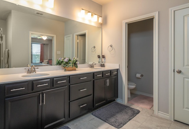 bathroom featuring double vanity, toilet, baseboards, and a sink