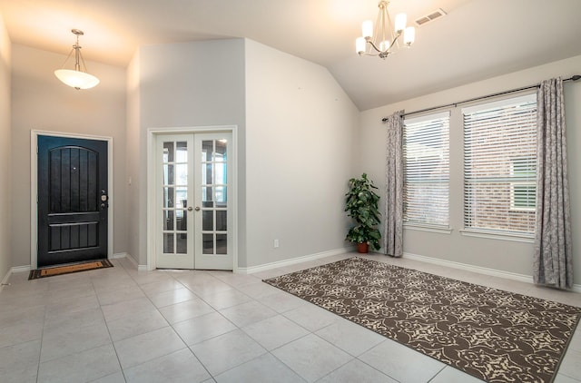 entrance foyer featuring light tile patterned flooring, vaulted ceiling, an inviting chandelier, and french doors