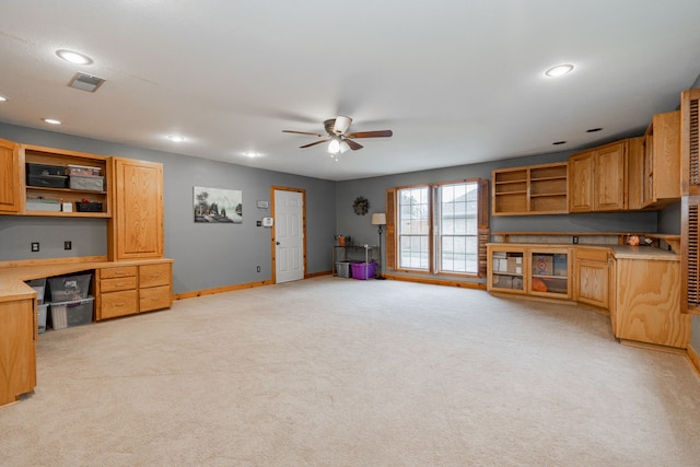 kitchen featuring ceiling fan, light colored carpet, and built in desk