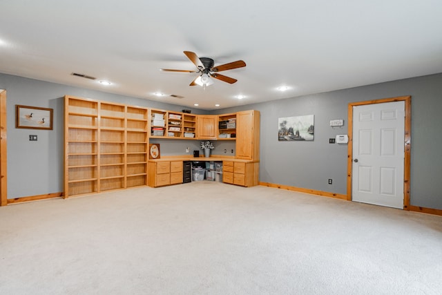 interior space with built in desk, light colored carpet, and ceiling fan