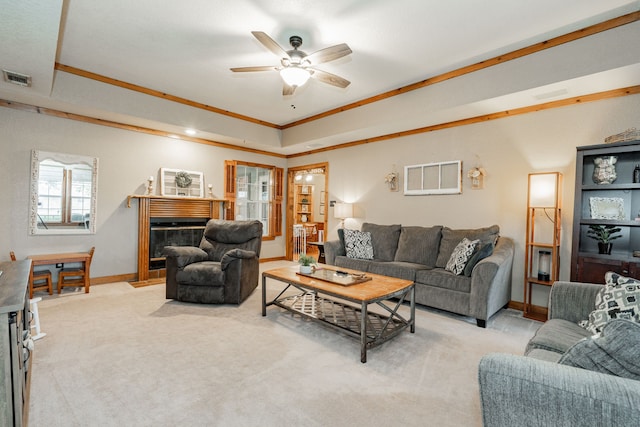 living room with a raised ceiling, ornamental molding, light colored carpet, and ceiling fan