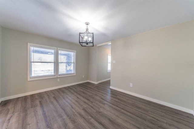 spare room with dark wood-type flooring and a notable chandelier