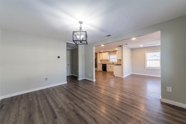 unfurnished living room featuring dark hardwood / wood-style floors and a notable chandelier