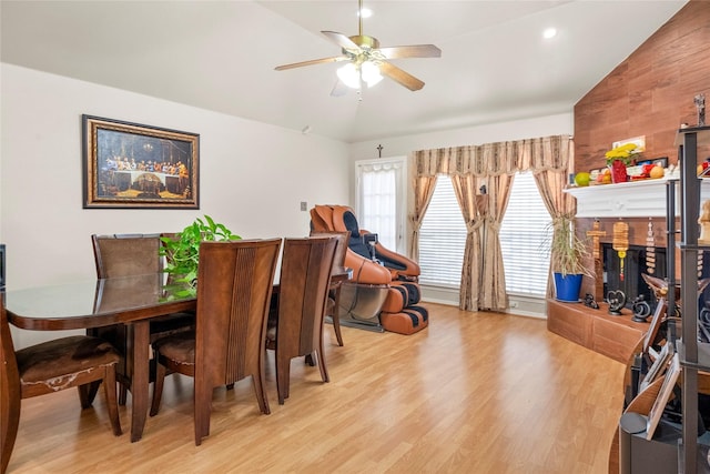 dining space with light hardwood / wood-style flooring, a fireplace, vaulted ceiling, and ceiling fan