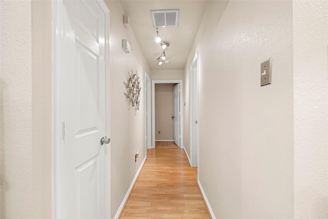 hall with rail lighting and light hardwood / wood-style flooring