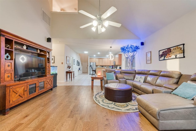 living room with ceiling fan, high vaulted ceiling, and light wood-type flooring