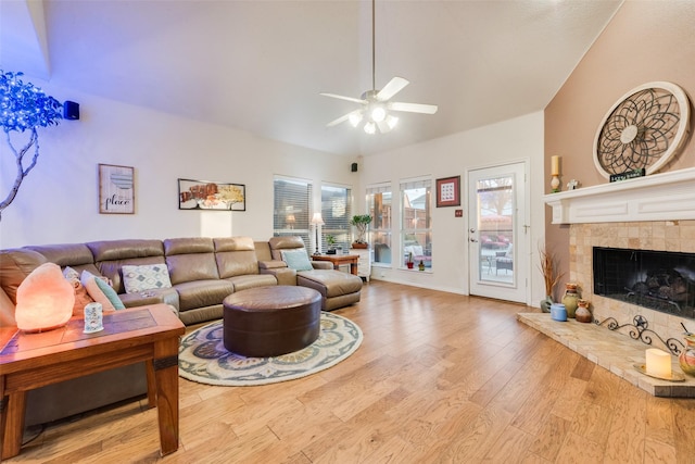 living room with ceiling fan, a tile fireplace, light hardwood / wood-style flooring, and a wealth of natural light