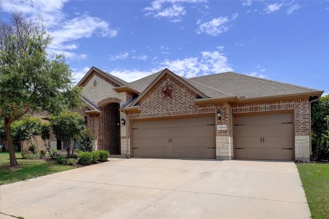 french provincial home featuring an attached garage, brick siding, a shingled roof, stone siding, and driveway