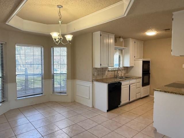 kitchen featuring white cabinets, a chandelier, hanging light fixtures, black appliances, and a raised ceiling