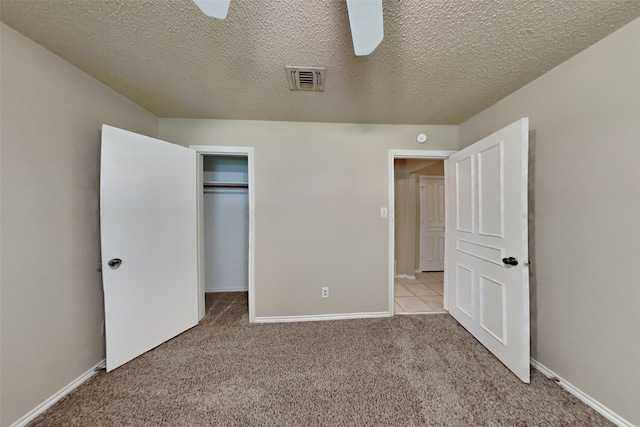 unfurnished bedroom featuring ceiling fan, light colored carpet, a closet, and a textured ceiling