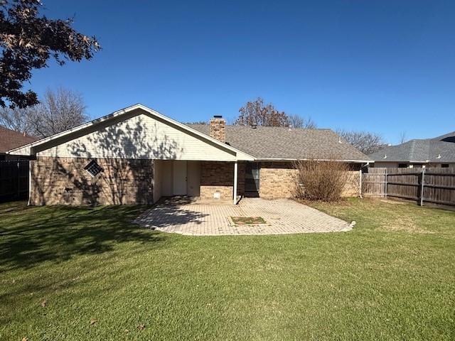 rear view of property featuring a yard and a patio area