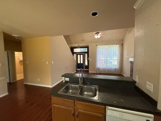 kitchen with dark wood-type flooring, sink, white dishwasher, a tile fireplace, and ceiling fan