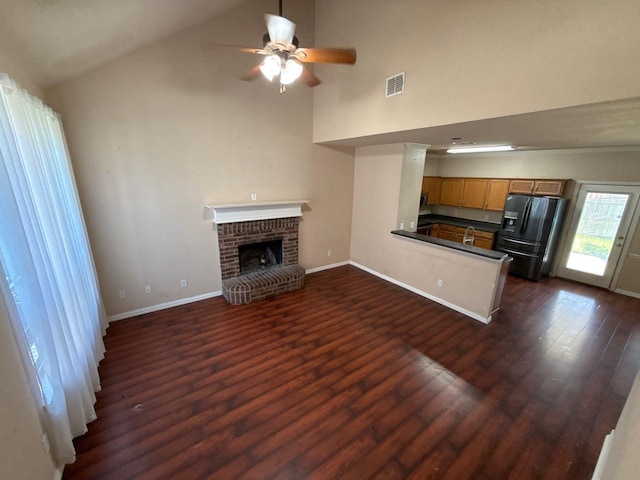 unfurnished living room featuring lofted ceiling, a brick fireplace, dark hardwood / wood-style floors, and ceiling fan