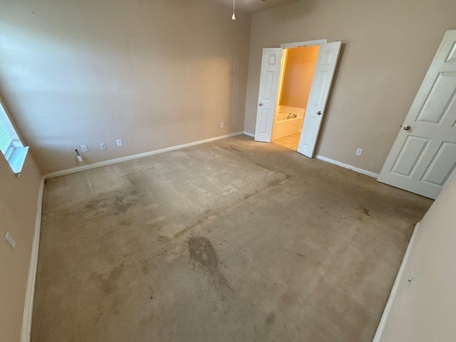 unfurnished bedroom featuring ensuite bathroom and light carpet