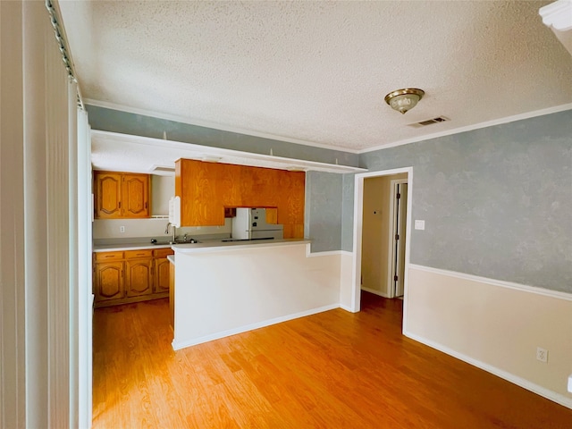 kitchen featuring sink, white fridge, light hardwood / wood-style floors, crown molding, and a textured ceiling