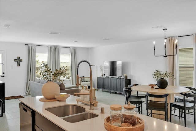 kitchen featuring open floor plan, light countertops, stainless steel dishwasher, a chandelier, and a sink