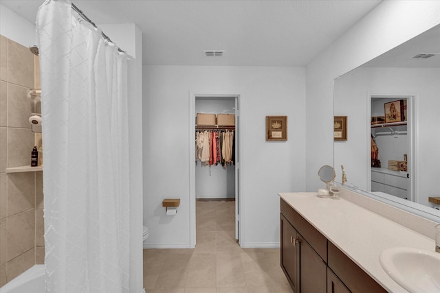 bathroom with tile patterned floors, visible vents, a walk in closet, and vanity